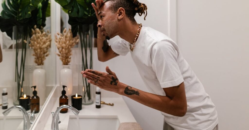 best facial cleanser for men A man washing his face in a stylish bathroom mirror, part of his morning beauty routine.