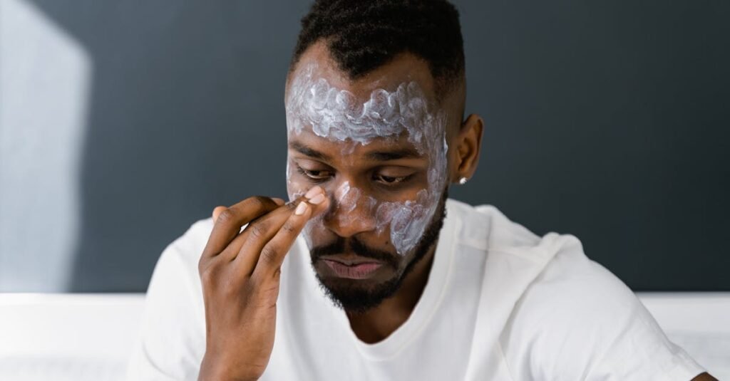 men's face moisturizer for daily use African American man applying facial cream, focusing on self-care and skin health.