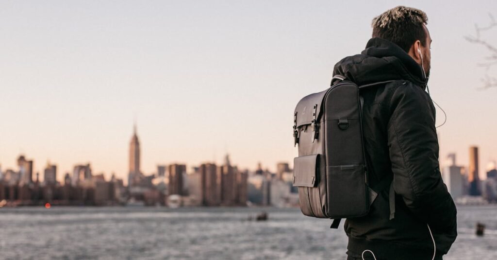 everyday carry backpacks with outdoor features A man wearing a backpack gazes at the Manhattan skyline from Brooklyn waterfront during the day.